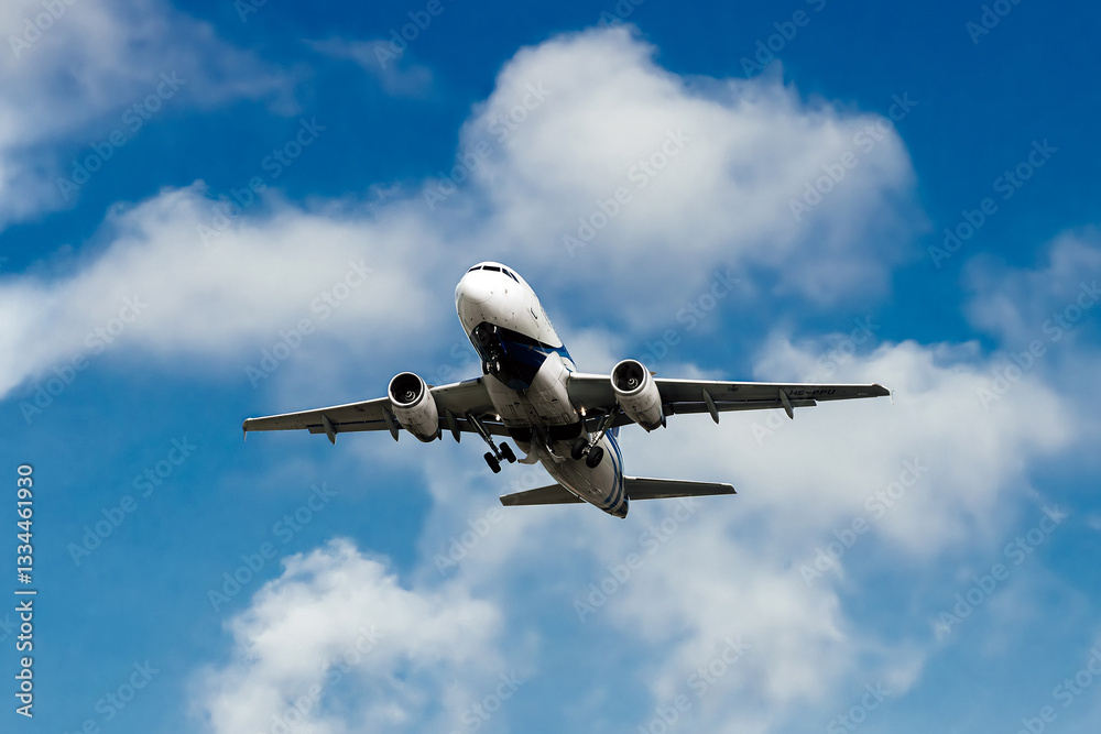 The plane flies through a clear blue sky, surrounded by fluffy white clouds. Travel and adventure concept. The plane flies through a clear blue sky, surrounded by fluffy white clouds. Travel and adventure concept.