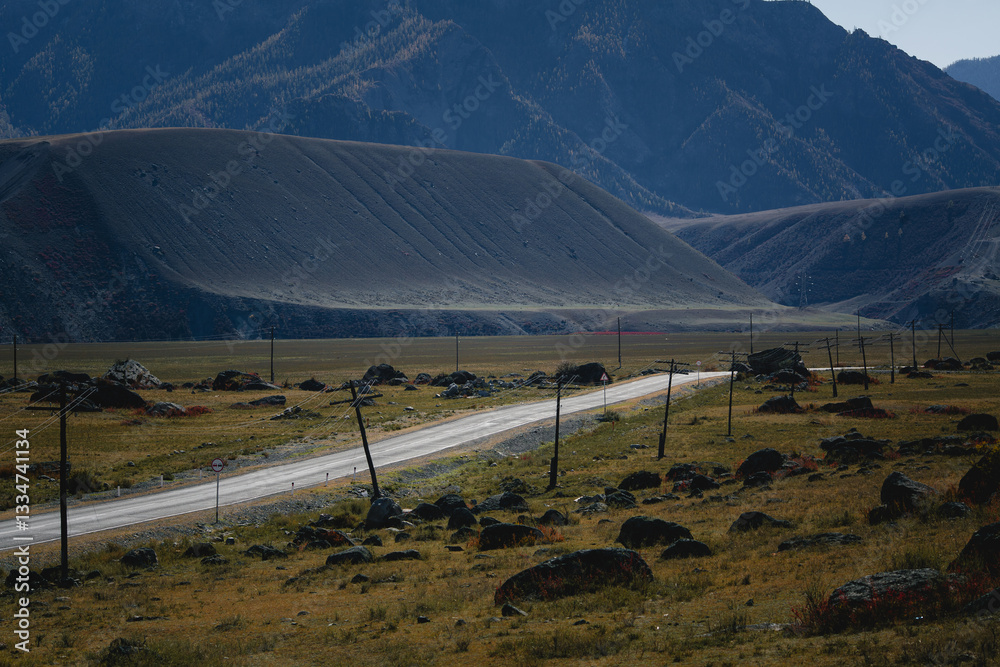 A winding road cutting through the majestic mountains of the Altai Republic, surrounded by breathtaking natural beauty.