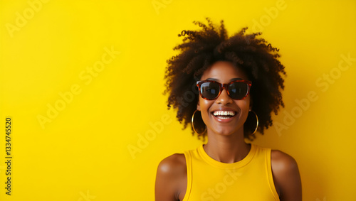 Cheerful Young African American Woman in Brown Sunglasses Against Yellow Wall: Capturing Vibrant Summer Vibes and Confident Brand Identity in Stock Photo