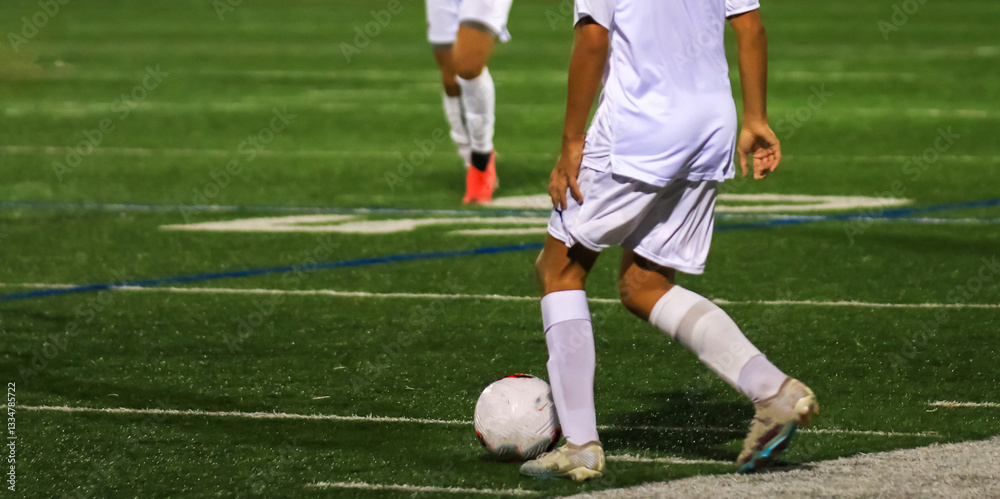 Young Soccer Player Prepares to Kick the Ball During a Night Game on a Well-Lit Field Young Soccer Player Prepares to Kick the Ball During a Night Game on a Well-Lit Field