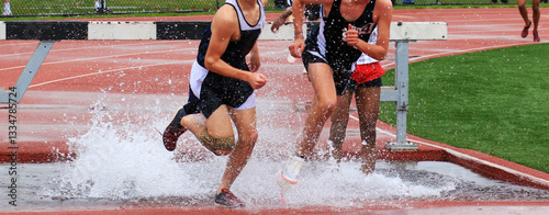 фотографія Runners Compete in a Steeplechase Race Splashing Through Water Obstacles During