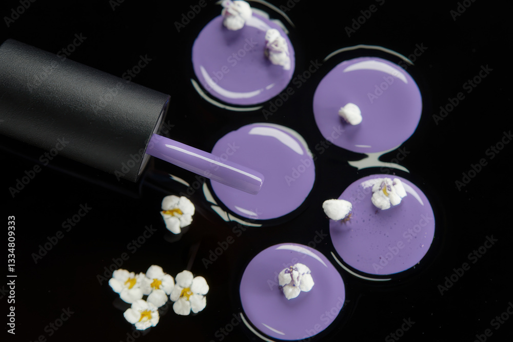Fototapeta premium Open black nail polish bottle with a brush dripping lavender polish onto a dark surface with small flower accents