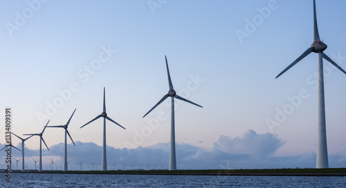 Row of offshore wind turbines against dark sky blue in Netherlands