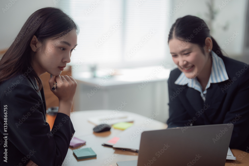 Two Asian businesswomen collaborating in a modern office, working together on a laptop while discussing and sharing innovative ideas for their project and strategies Two Asian businesswomen collaborating in a modern office, working together on a laptop while discussing and sharing innovative ideas for their project and strategies