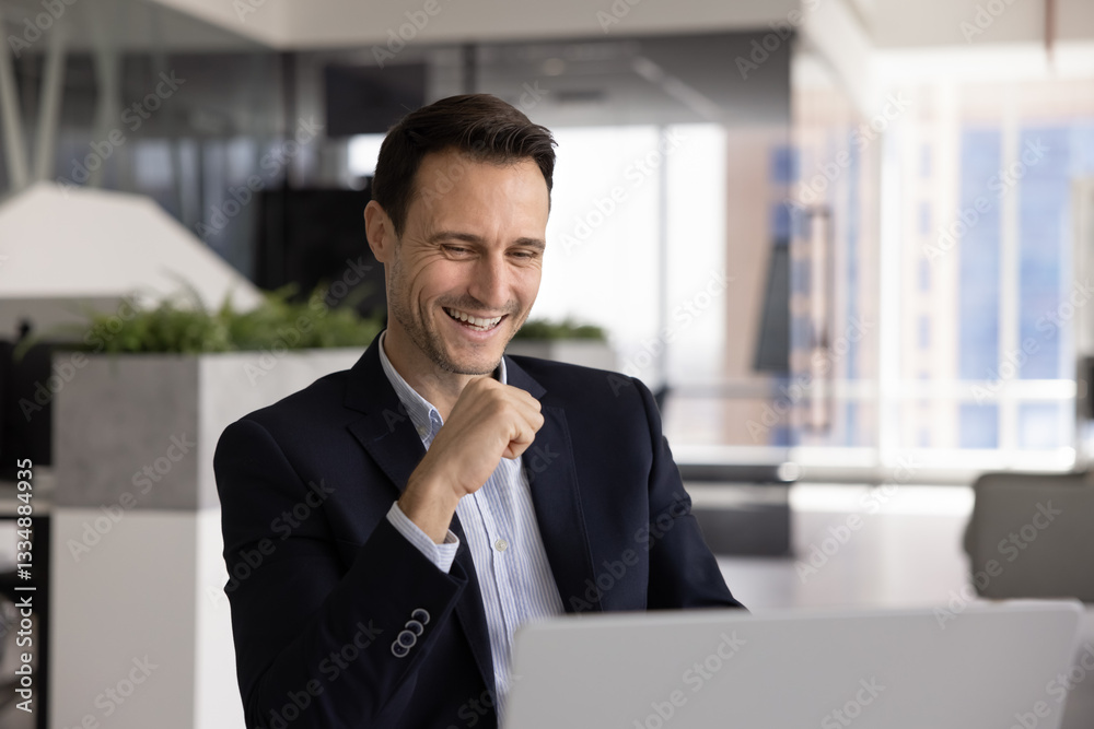 Cheerful successful business professional man using computer for communication, watching online content, getting good news, laughing, enjoying modern Internet technology for work Cheerful successful business professional man using computer for communication, watching online content, getting good news, laughing, enjoying modern Internet technology for work
