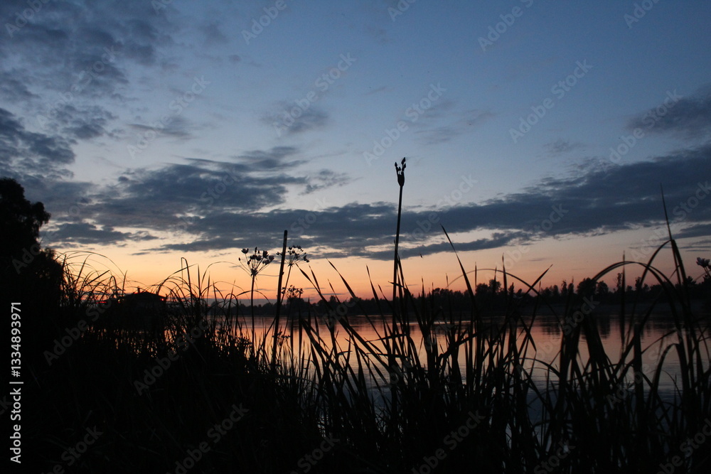 Obraz premium dark silhouettes against the background of a sunset over the river. Evening Landscape