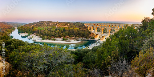 Pont du Gard, ancient Roman aqueduct bridge, elevated panoramic view, river bend and arches, early morning golden light, Gorges du Gardon, natural landscape, UNESCO Biosphere Reserve, Provence, France