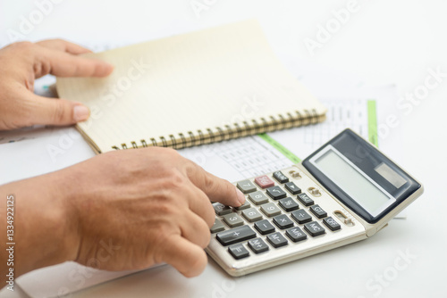 Hand pressing buttons on calculator while preparing financial reports in an office setting