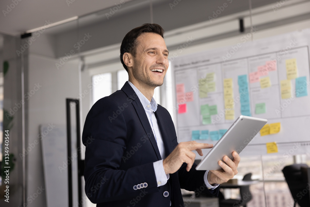 Happy successful Hispanic executive man using tablet in office, holding digital device, typing, looking away, smiling, laughing, thinking on professional success, job achievement, company growth Happy successful Hispanic executive man using tablet in office, holding digital device, typing, looking away, smiling, laughing, thinking on professional success, job achievement, company growth