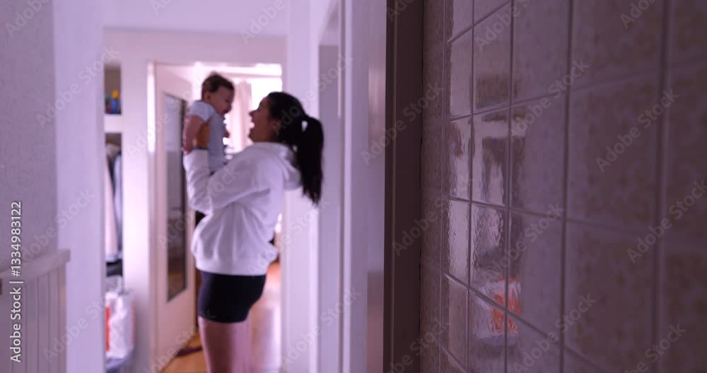Silhouette of mother lifting baby in hallway, blurred in background, home interior, reflection on patterned wall tiles, candid authentic lifestyle scene, intimate family moment Silhouette of mother lifting baby in hallway, blurred in background, home interior, reflection on patterned wall tiles, candid authentic lifestyle scene, intimate family moment