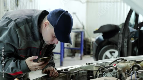 Professional mechanic capturing car engine details using smartphone while performing diagnostic work in modern auto repair workshop