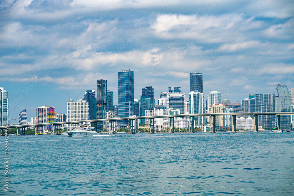 Fototapeta premium Miami Skyline: The iconic Miami skyline stretches along the coast, with modern skyscrapers piercing the sky above the tranquil waters, creating a captivating cityscape.