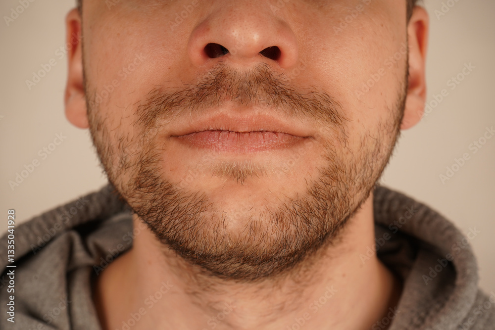 Obraz premium The unshaven look exudes effortless charm and simplicity. Perfect for themes of grooming and casual style. A detailed close-up of a man's chin with subtle stubble, showcasing masculine appeal.