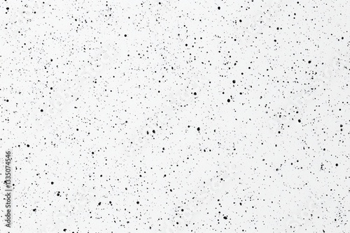 Abstract speckled white surface.  Small black specks scattered randomly on a white background