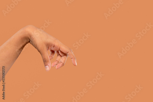 Hand gracefully extended against a warm brown background showcasing delicate fingers in relaxed position photo