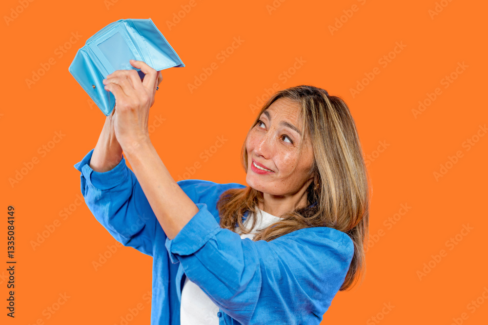 Woman joyfully looking inside an empty blue wallet against a vibrant orange background while expressing surprise and curiosity Woman joyfully looking inside an empty blue wallet against a vibrant orange background while expressing surprise and curiosity
