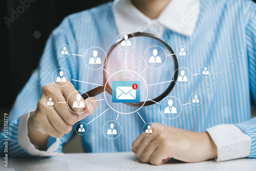 Person Examining Contacts Through Magnifying Glass with Email Notification in Office Setting, Business concept