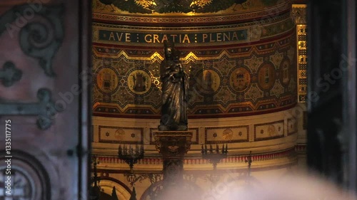 A framed view of a Virgin Mary statue trough the Door of Notre-Dame de la Garde in Marseille. The golden mosaics and intricate details of the church interior create a sacred atmosphere.