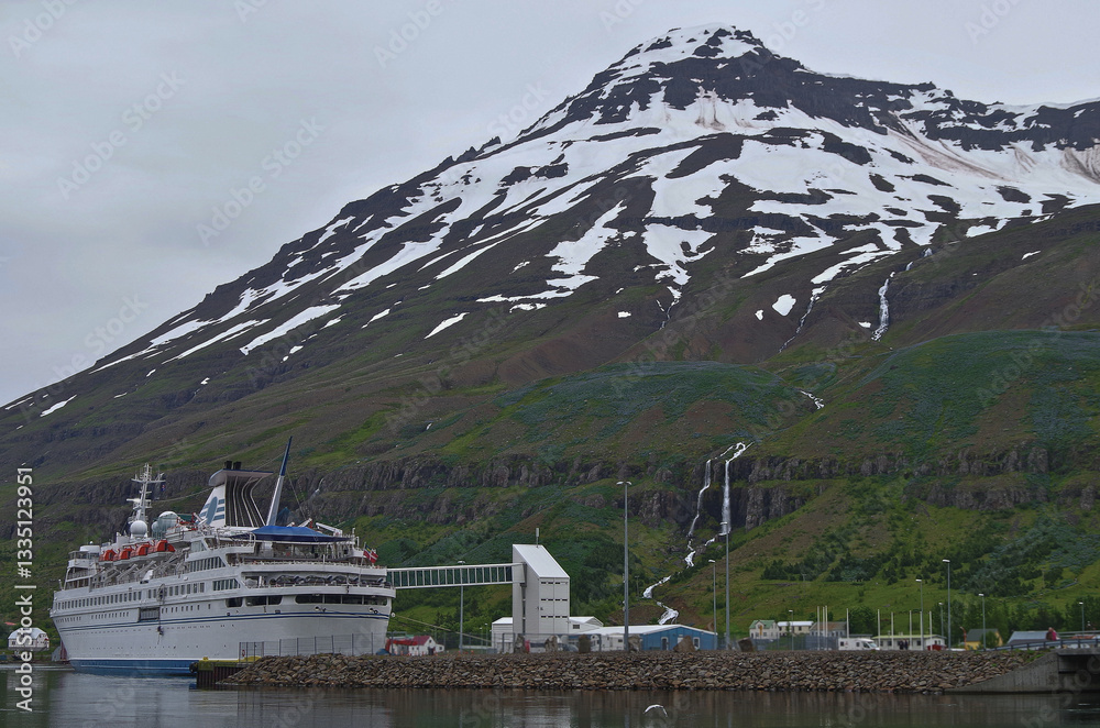 Classic expedition cruiseship cruise ship liner Delphin docked at pier in Seydisfjördur, Iceland with harbor skyline and fjord landscape in background on during Arctic Circle summer cruising