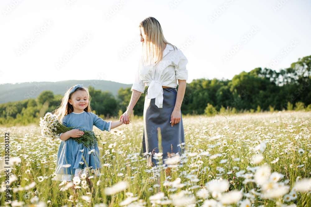 Fototapeta premium Mother playing with child girl 4-5 year old in blooming chamomile meadow wearing casual dresses outdoors. Springtime. Motherhood.