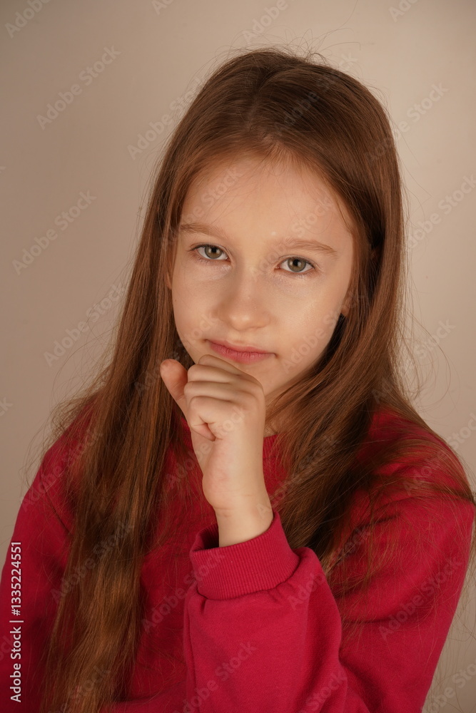 The pose highlights her serenity. The little girl rests her chin on her clenched fist, looking relaxed and calm. Her expression conveys a sense of ease as she takes a peaceful moment. The pose highlights her serenity. The little girl rests her chin on her clenched fist, looking relaxed and calm. Her expression conveys a sense of ease as she takes a peaceful moment.
