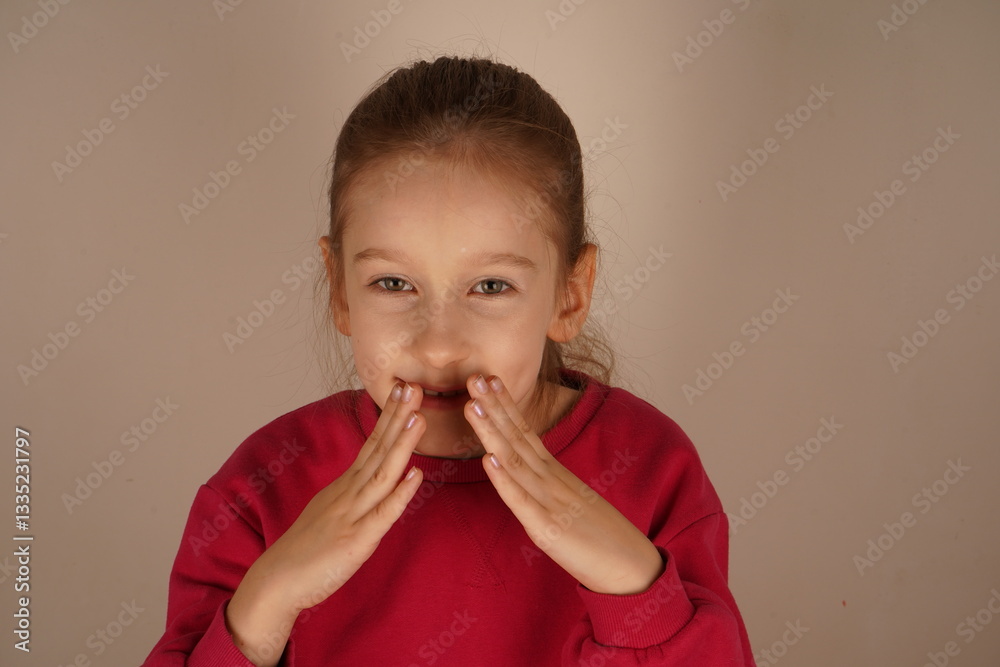 Her playful expression radiates happiness and creativity. A delightful gesture capturing her carefree mood. With hands near her mouth, the girl pretends to shape a smile. Her playful expression radiates happiness and creativity. A delightful gesture capturing her carefree mood. With hands near her mouth, the girl pretends to shape a smile.