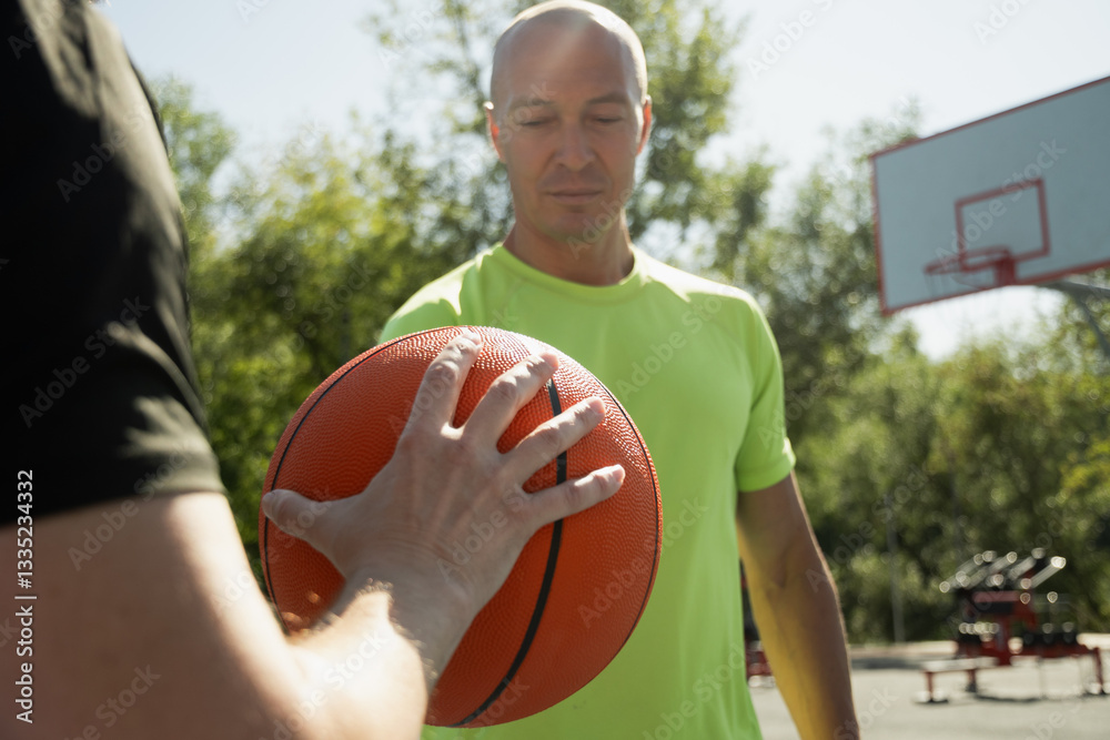 Two basketball players holding orange ball on sports court. Sports goals competition game, champion outdoor workout. Game moment. Close up.