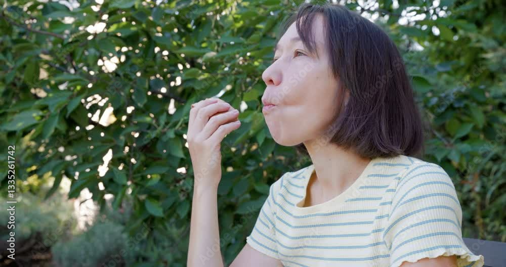 Woman sits at the table eating food outdoor in backyard garden Woman sits at the table eating food outdoor in backyard garden