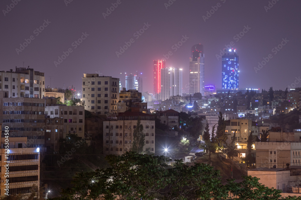 Fototapeta premium Night panorama of Amman city downtown streets with neon glowing skyscrapers, Kingdom of Jordan