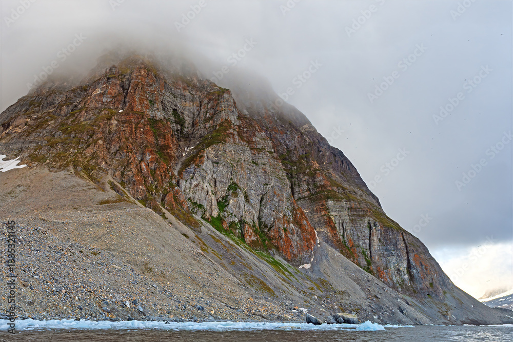Colorful Coastal Peak Rising From Arctic Waters Into the Fog