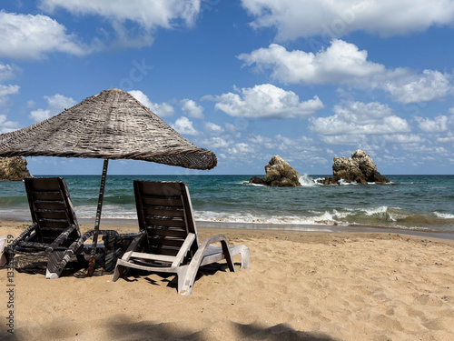 Fototapeta Naklejka Na Ścianę i Meble -  A tranquil beach scene featuring two chairs and umbrella on golden sand under a bright blue sky. Sile, Turkey. Black Sea view, with empty place