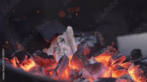 Close up of bokeh embers that burn in a barbecue in slow motion