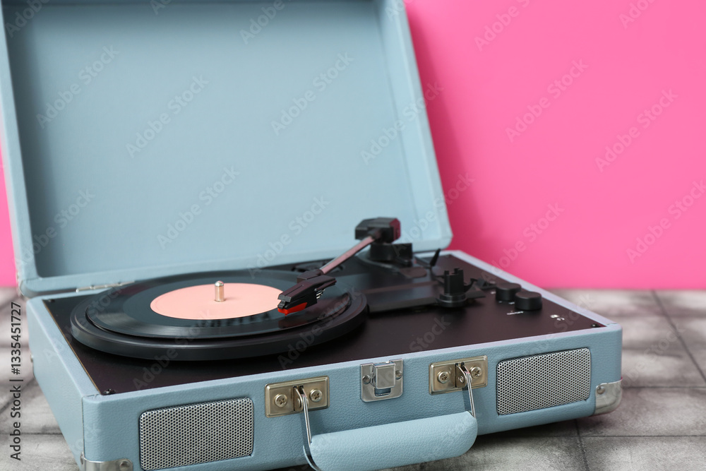 Obraz premium Record player with vinyl disk on table near pink wall