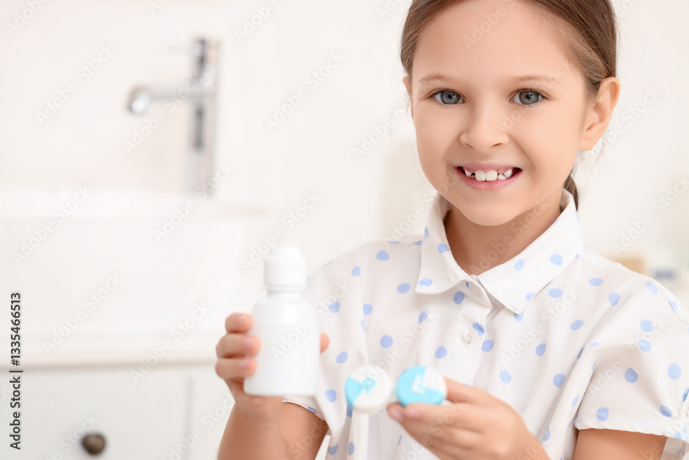 Cute little girl with contact lenses and bottle of solution in bathroom, closeup Cute little girl with contact lenses and bottle of solution in bathroom, closeup