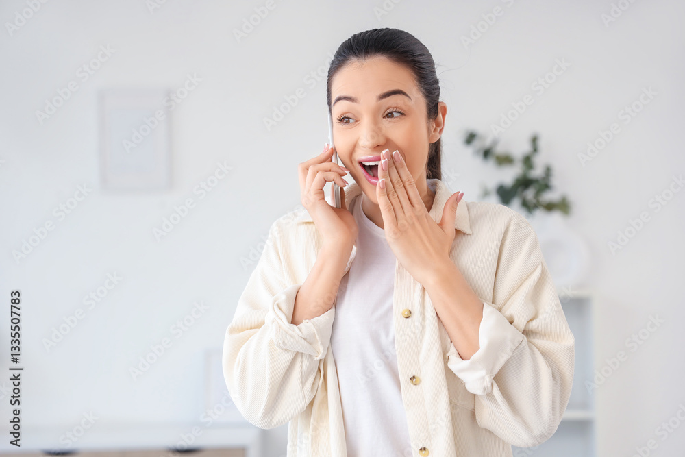 Surprised young woman talking by mobile phone at home Surprised young woman talking by mobile phone at home