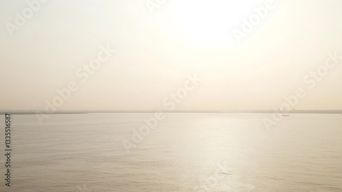 Calm sea at sunrise, hazy horizon.