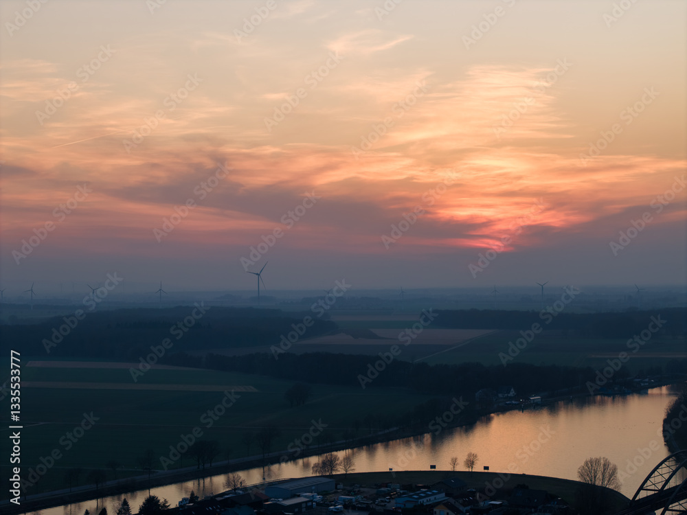 The sunset casts a golden glow over a tranquil landscape with a river and wind turbines Hannover Seelze The sunset casts a golden glow over a tranquil landscape with a river and wind turbines Hannover Seelze