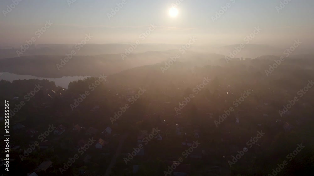 Sun Rays Break Through Foliage Fog of Trees. Early Morning Fog Rising up Above Shiny Hills. Scenic Aerial View of Village Foggy Morning in Poland. Amazing Nature Landscape Wonderful Morning Sunrise. Sun Rays Break Through Foliage Fog of Trees. Early Morning Fog Rising up Above Shiny Hills. Scenic Aerial View of Village Foggy Morning in Poland. Amazing Nature Landscape Wonderful Morning Sunrise.
