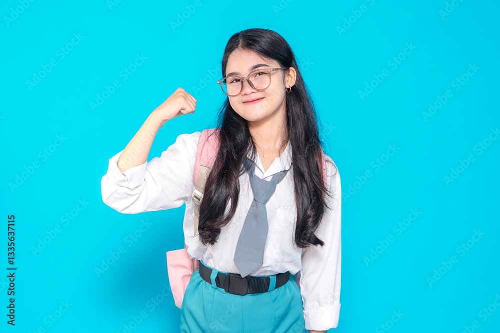 An Indonesian high school student in a school uniform with glasses and a backpack, smiling confidently while flexing her arm in a strong gesture. She exudes determination and positivity