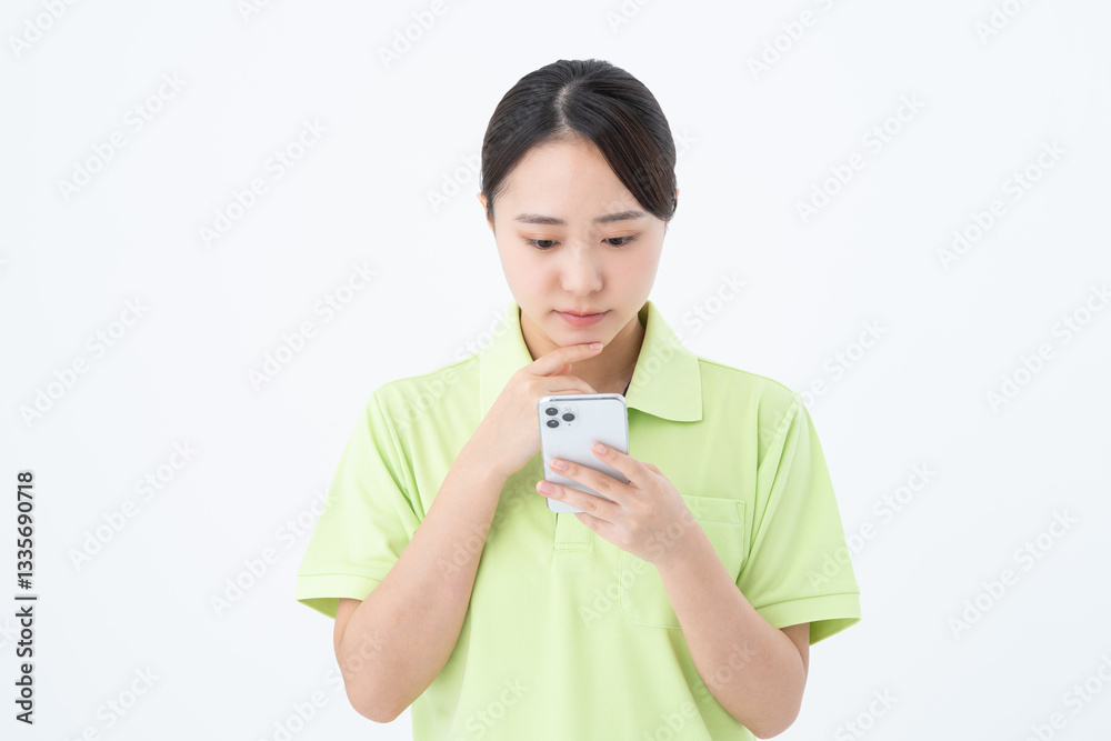 スマホを使う若い介護福祉士の女性 スマホを使う若い介護福祉士の女性