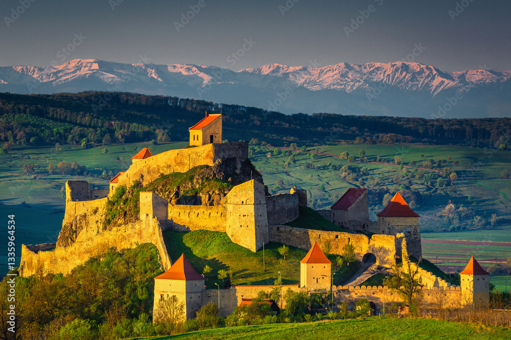 Rupea fortress on the hill and snowy mountains in background