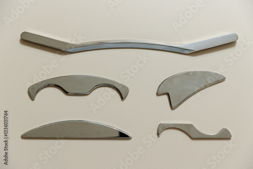 Intelligent stainless steel IASTM instruments for soft tissue massage and pain relief, the instruments lie on a beige massage table