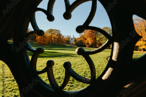 View of the autumn trees through the Gothic ornament of the ancient well, the Gothic church in the park. Autumn in a public park