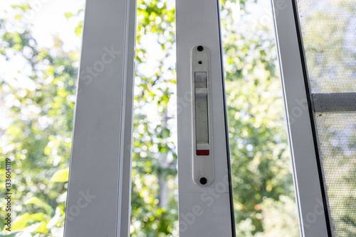 Close-up of a double-glazed balcony frame with a latch and fastening for safe ventilation. Single-sided window handle. House door and window repair concept