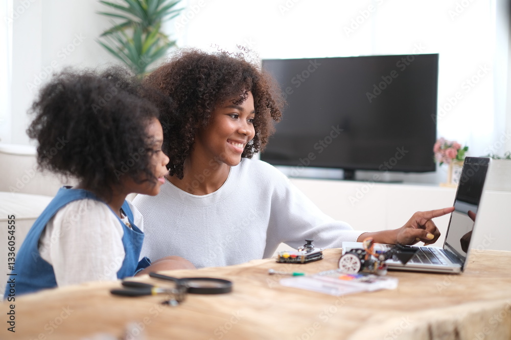 Naklejka premium African loving mother and daughter team up for fun robotics project at home, exploring hands-on STEM activities that inspire creativity, and early engineering skills, fostering problem-solving skills