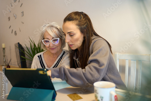 Woman helping senior mother using digital tablet at home