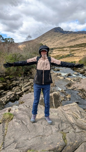 Beautiful woman backpacker in hooded jacket hiking at river Erriff near Aesleagh, county Mayo, Ireland, Irish landscape, mountains and nature background photo