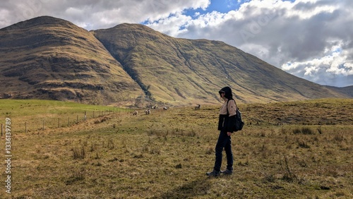Beautiful woman backpacker in hooded jacket hiking at river Erriff near Aesleagh, county Mayo, Ireland, Irish landscape, mountains and nature background	