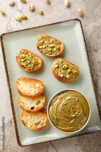 Obraz na płótnie Healthy pistachio butter and toasted bread close-up on plate on table. Vertical top view from above w salonie