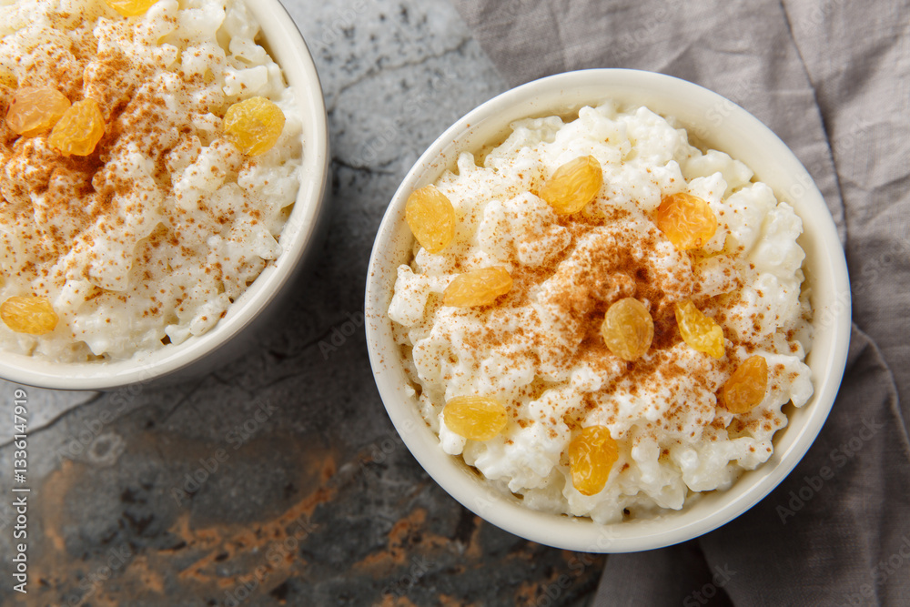 Sweet rice pudding with cinnamon and raisins on top close-up in a ramekin on the table. Horizontal top view from above